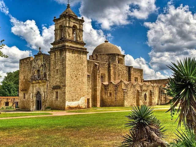 Mission San Jose building with bell tower and dome under cloudy sky