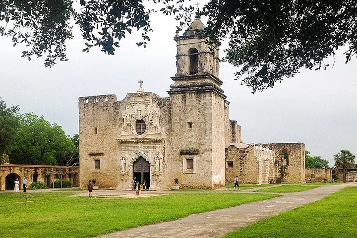 Mission San Jose stone church with bell tower and people walking around