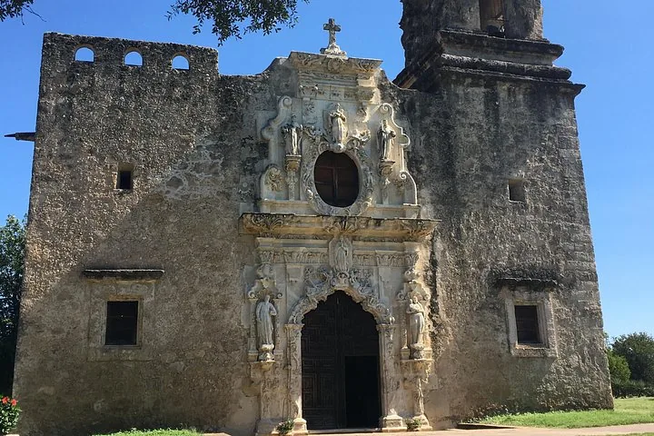 Stone facade of Mission Concepcion with statues and carvings around the door