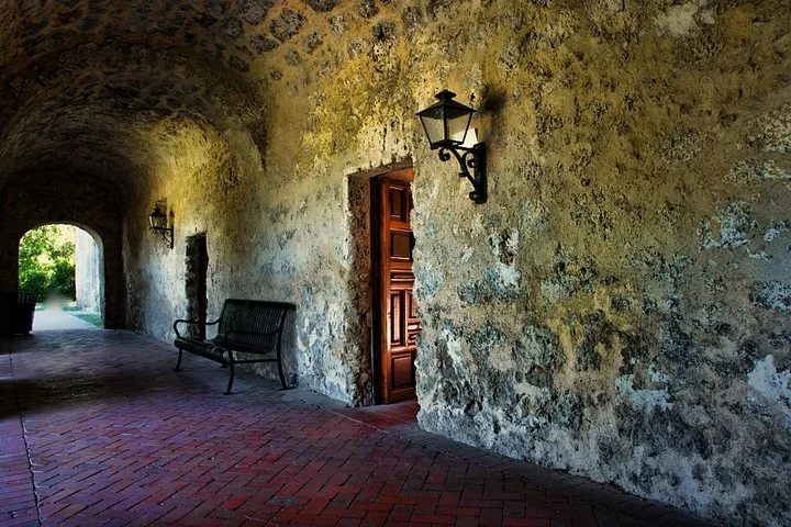 Stone arched walkway with a wooden door and a bench